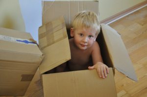 A boy sitting in a moving box.